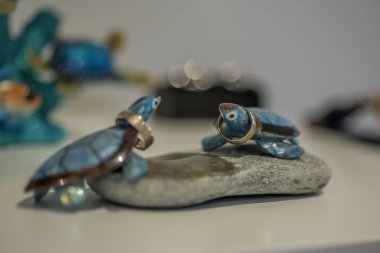 Yuvarlak taş dekorasyon alyans tutan iki mavi cheramic kaplumbağalar.