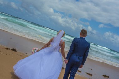 Deniz kenarında güzel kumlu plajda buket tutan sadece evli çift.