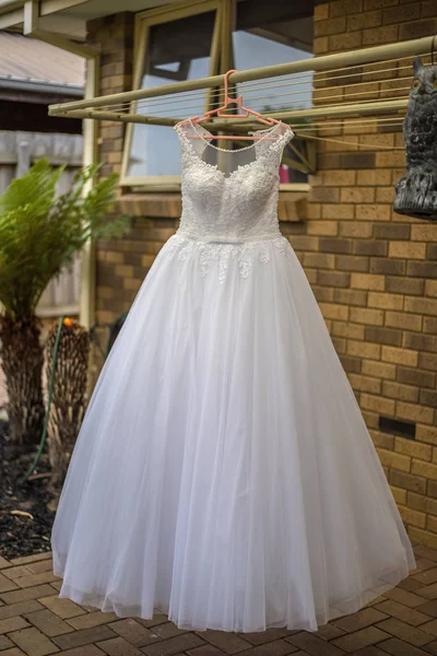 Düğün için bekleyen asılı beyaz gelinlik.