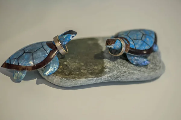 Yuvarlak taş dekorasyon alyans tutan iki mavi cheramic kaplumbağalar.