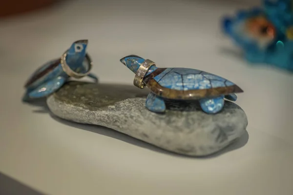 Yuvarlak taş dekorasyon alyans tutan iki mavi cheramic kaplumbağalar.