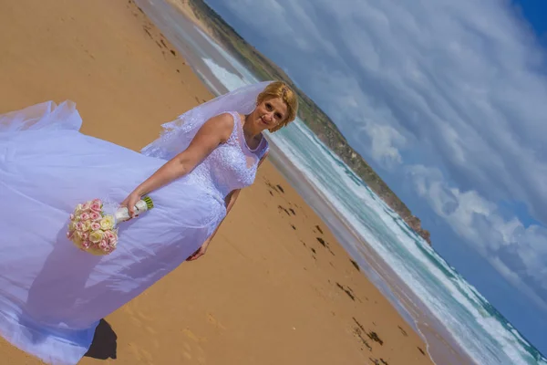 Güzel kumlu plajda durup beyaz gelinlik içinde gelin.