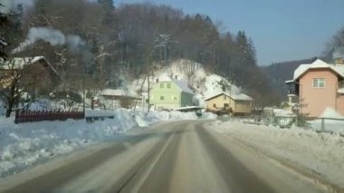 Güzel kış sabahı yerleşmesi ile sürüş. Güneş parlıyor ve duman bacaları dışarı geliyor. Karla kaplı çatıları.