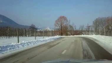 Çiftlik topraklarda kar ile kaplı araç önden görünüm içinde filme. Yol elma meyve bahçeleri ile gidiyor.