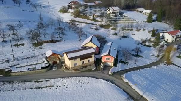 Aéreo Voando Sobre Estrada Colinas Cobertas Neve Com Poucas Casas — Vídeo de Stock