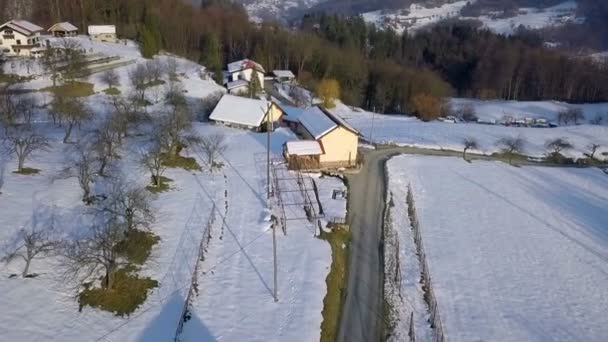 Aéreo Voando Sobre Estrada Colinas Cobertas Neve Com Poucas Casas — Vídeo de Stock