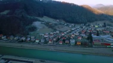 Hava: Nehri yakınında küçük şehir soğuk kış sabahı gösterilen. Güneş yükseliyor ve arka plan tepelerde parlayan.