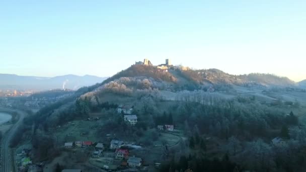 航空写真 凍るような冬の寒い朝に市ではスロベニアのツェリェ城に向かって飛んでください 背景の丘に輝く日の出 — ストック動画