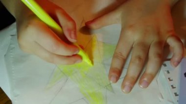 Küçük kız bir kağıt yıldız sarı marker ile boyama kalem ağır çekimde. Noel süslemeleri çocuklu yaparken filme.
