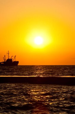 Denizde günbatımında yola çıkmak.