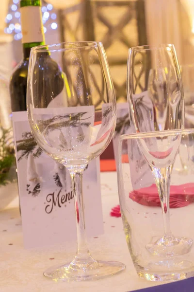 Reception and party table, with wine glass, water glass and champagne glass, menu and bottle of wine