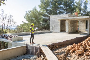 Çırak zanaatkar, inşaat aşamasında ki evin şantiyesindeki bir planı kontrol altına alan inşaat ticareti