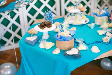 Çocuk tatil mavi balonlar, kabukları ve yeşil bitkiler ile güzel bir çikolata deniz tarzında küçük bir Doğum günü için mavi bir pasta ile dekore edilmiştir. Küçük bir çocuk için bir parti