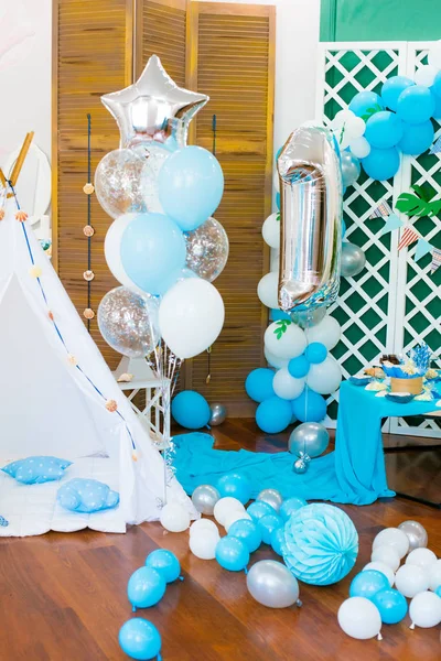 The children\'s holiday is decorated with blue balloons, seashells, and green plants, a beautiful candy bar with a blue cake for a small birthday in a marine style. A party for a little boy