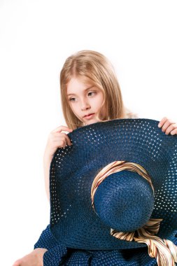 Geniş ağzına kadar ile şapkalı sarışın saçlı ve beyaz zemin üzerine stüdyoda uzun şık bir etek güzel şık küçük kız