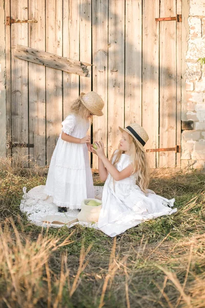 Preciosas Hermanas Rubias Vestidos Blancos Sombreros Paja Ríen Comen Manzanas — Foto de Stock