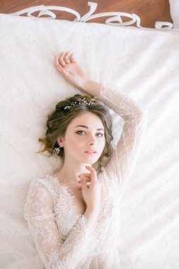 Güzel gelin portresi. Sabah gelin. Düğün sabah. Makyaj. Gelinle koniler ve sarı saçlar. Beyaz dantel sabahlık içinde kırılgan gelin