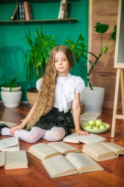 Tatlı bir kız öğrenci kitap, okul yönetimi ve elma ile uzun sarı saçlı küçük sınıfların. Okul moda