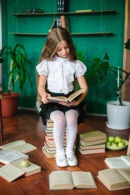 Tatlı bir kız öğrenci kitap, okul yönetimi ve elma ile uzun sarı saçlı küçük sınıfların. Okul moda