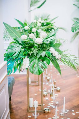 Düğün süslemeleri bir tropikal tarzı unsurları. Kadının küçük özel odası süslemeleri tropikal yaprakları ve beyaz orkide, gül, dışkı ve mumlar