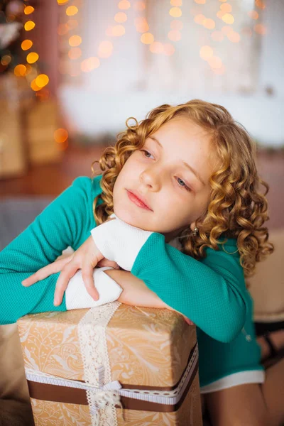 金髪巻き毛の家庭で装飾が施された暖炉と花輪ギフト クリスマス ツリー近くかわいい女の子 — ストック写真
