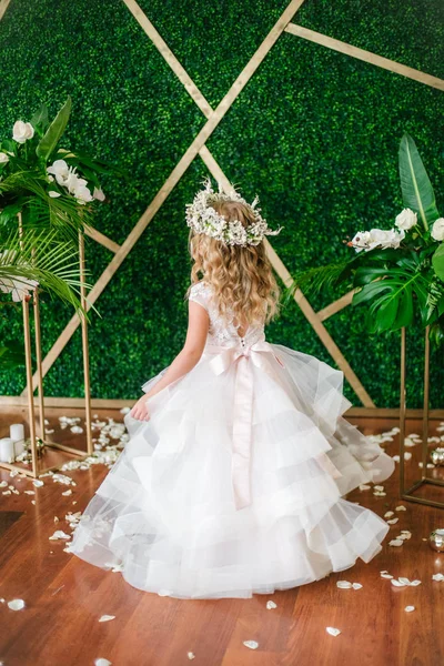 Beyaz gelinlik ve çelenk çiçek süslemeleri yapılmış tropik yapraklar, beyaz güller ve orkide çiçek dolu sarışın kıvırcık saçlı sevimli küçük kız