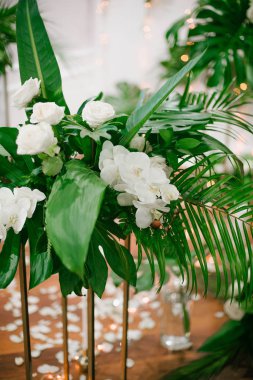 Beyaz güller ve orkide düğün buket ve onların çiçek düğün dekorasyonu, tropikal yaprak ve mumlar