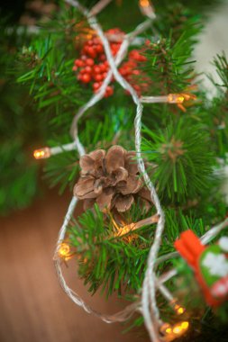 Noel çelenk koniler ve kırmızı meyveler ve çelenk ışık ve oyuncaklar ile iğne yapraklı şube