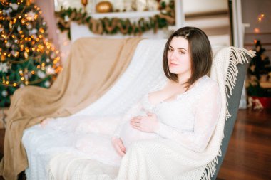 gebelik, bayram, insanlar ve beklenti kavramı - oturma ve karnı evde Noel ağacı arka plan üzerinde dokunmadan mutlu hamile kadın