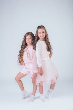 Sevimli küçük kız beyaz moda giysiler içinde kıvırcık saçlı ve pembe stüdyo