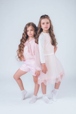 Sevimli küçük kız beyaz moda giysiler içinde kıvırcık saçlı ve pembe stüdyo