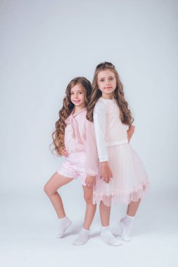 Sevimli küçük kız beyaz moda giysiler içinde kıvırcık saçlı ve pembe stüdyo