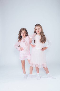 Sevimli küçük kız beyaz moda giysiler içinde kıvırcık saçlı ve pembe stüdyo