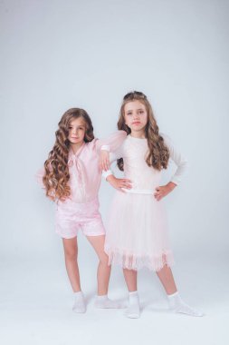 Sevimli küçük kız beyaz moda giysiler içinde kıvırcık saçlı ve pembe stüdyo