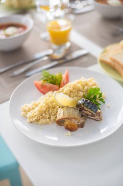 sebze ve portakal suyu ile beyaz tabakta Mısır, domates ve limon ile pişmiş balık ve rulo ile bulgur