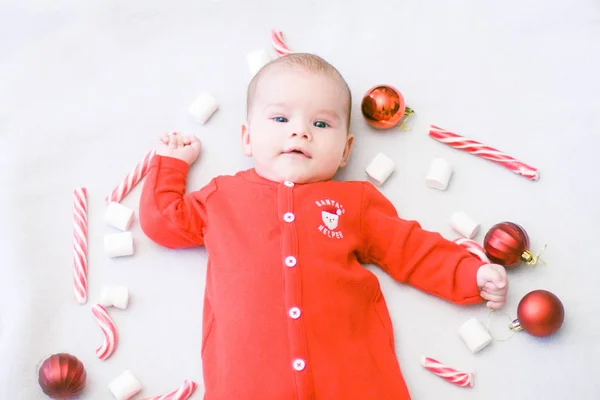 Baby first christmas. Beautiful little baby celebrates Christmas. New Year's holidays. Baby with Christmas candy and marshmallows . Santa baby. - Bilder