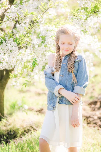 緑豊かな庭園で春に白いサンドレスで金髪のかわいい女の子 — ストック写真