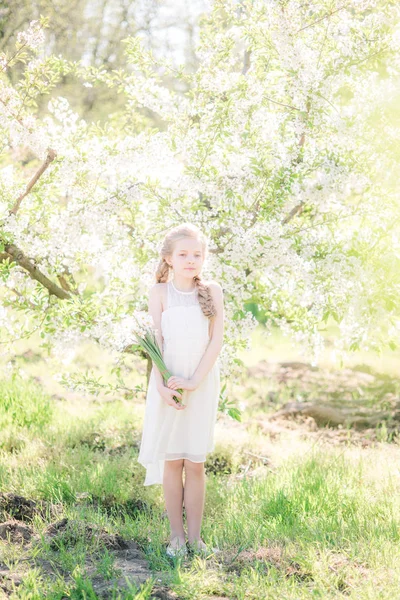 Cute Girl Blond Hair White Sundress Spring Lush Garden Daffodils — Zdjęcie stockowe