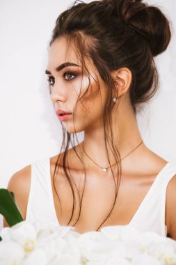 Güzel Asyalı kız akşam makyaj ve saç beyaz bir elbise ve orkide bir buket ile