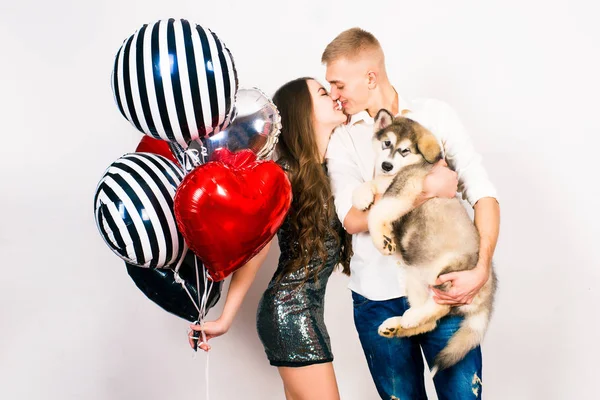 Kissing Par Poserar Grå Bakgrund Med Ballonger Hjärtan Och Malamute — Stockfoto