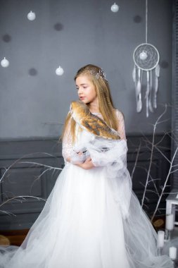 Beyaz baykuş kollarındaki ile beyaz elbiseli sarışın saçlı sevimli kız