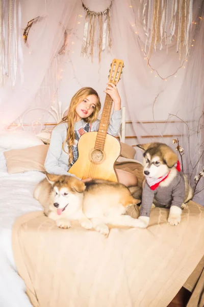 マラミュート子犬とベッドの上で長いブロンドの髪とかわいい女の子 — ストック写真