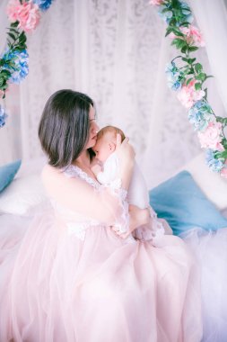 Bir kadının küçük özel odası elbiseli genç anne bahar çiçekleri gölgelik yatak tarafından kucağında bir bebekle