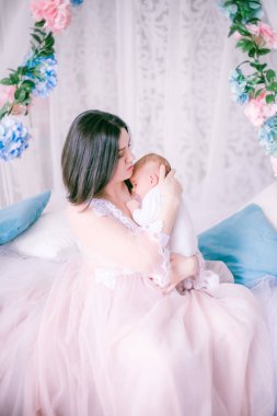 Bir kadının küçük özel odası elbiseli genç anne bahar çiçekleri gölgelik yatak tarafından kucağında bir bebekle