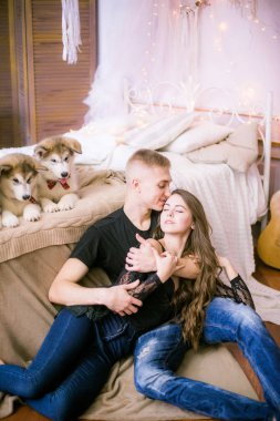 Neşeli genç sevgi dolu çift yatak odasında ifade ederken oturan Malamute kukla ile tr 