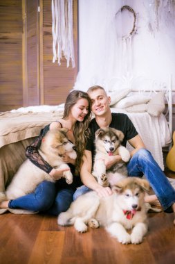 Neşeli genç sevgi dolu çift yatak odasında ifade ederken oturan Malamute kukla ile tr 