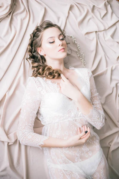 Young cute bride with beautiful hair in the morning at home in white lace negligee