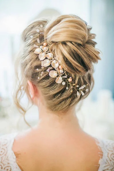 Young cute bride with a beautiful hairdo in the morning at home at the dressing table in white lace negligee