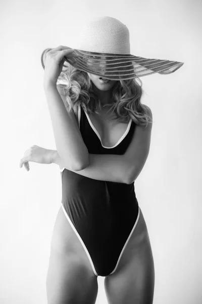 黒ヴィンテージ水着と白い背景の上のつばの広い麦藁帽子でブロンドの髪を持つ魅力的な少女 — ストック写真