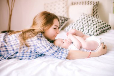 Gömlek ve mavi jeans erkek bebek onun yatak - görüntü ile oynarken güzel anne portresi